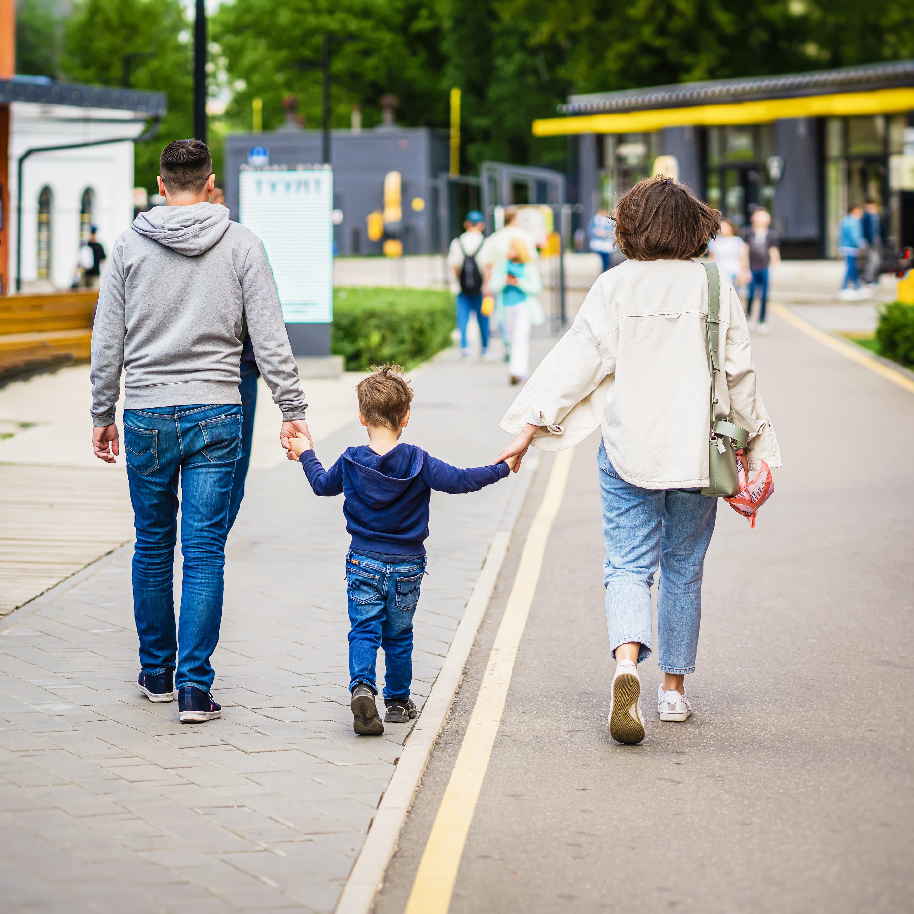 Young family walking hand-in-hand from behind